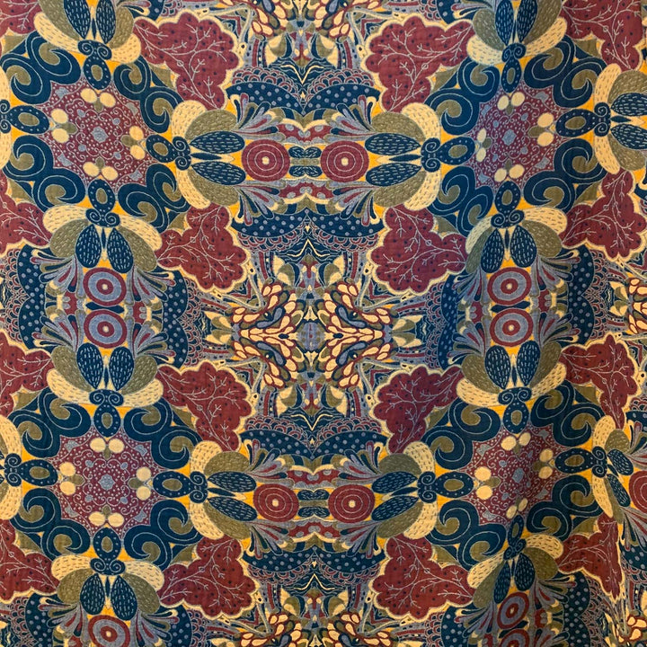 Fabric close-up of the reverse cool side of the Daphne blanket. Dark teal, berry red, and olive foliage form a dramatic and detailed symmetrical design, highlighted by pops of golden ochre.