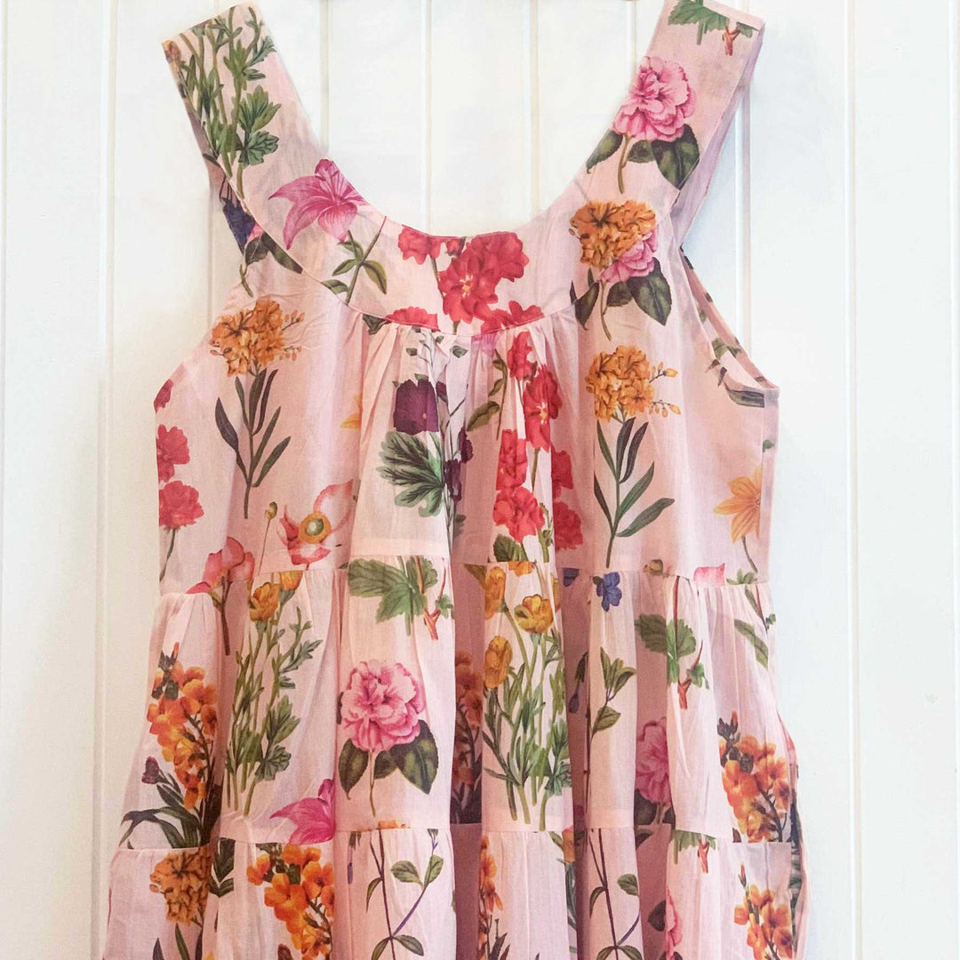 Flora nightie on white timber wall, showing floral pattern and pleating detail