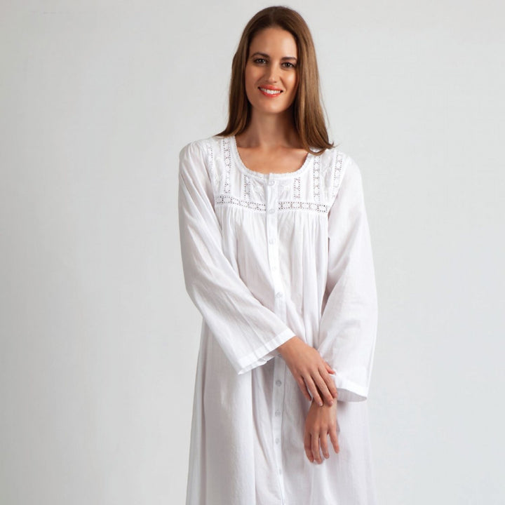 Woman wearing a classic white cotton nightie with lace detail and full button front.