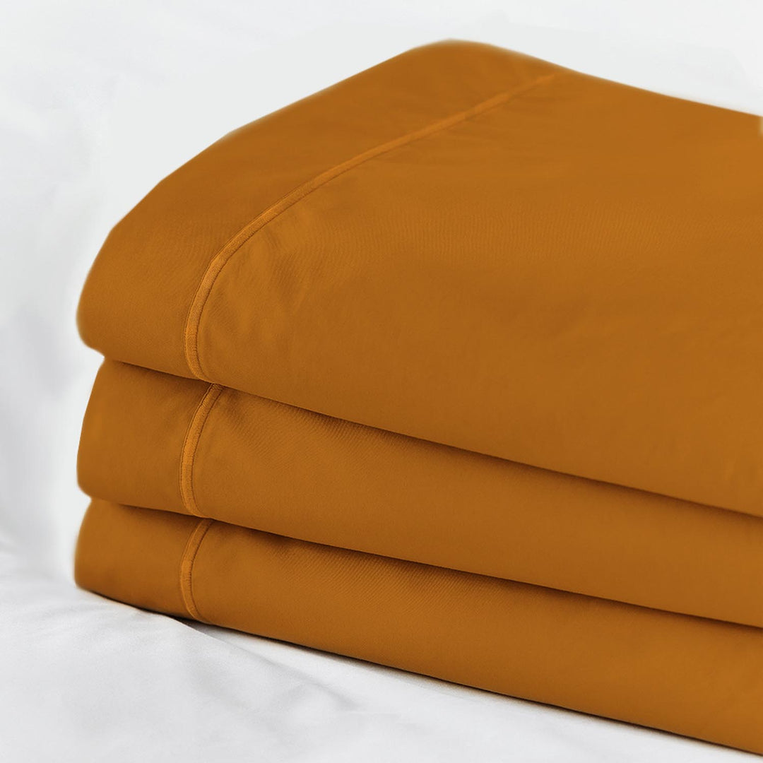 Bold mustard yellow Egyptian cotton fitted top sheet folded in stack