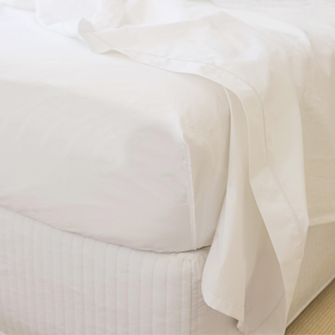 Close-up of white Egyptian cotton fitted top sheet corner tucked on mattress