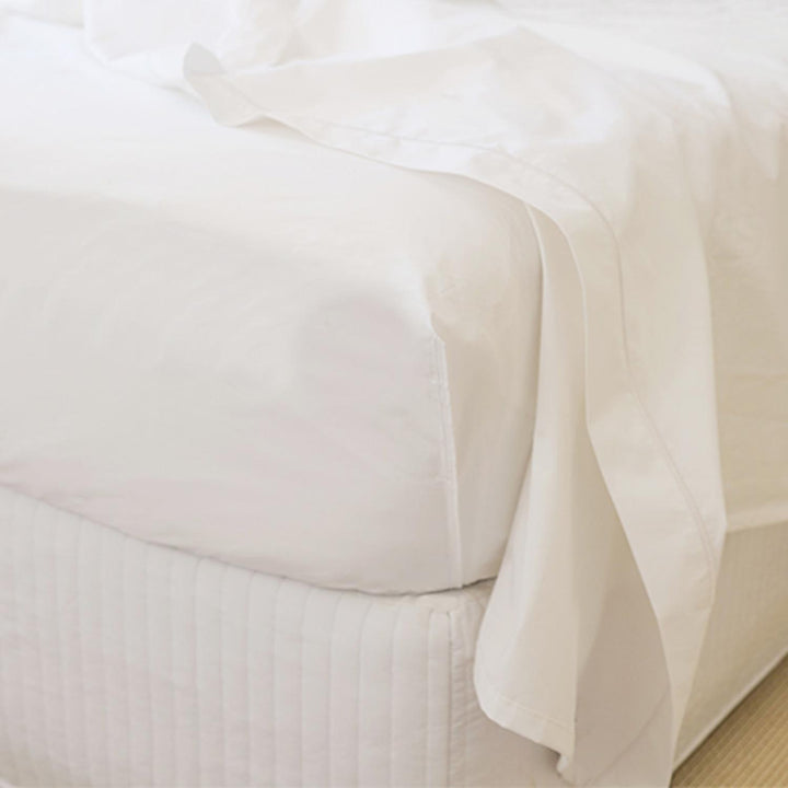 Close-up of white Egyptian cotton fitted top sheet corner tucked on mattress