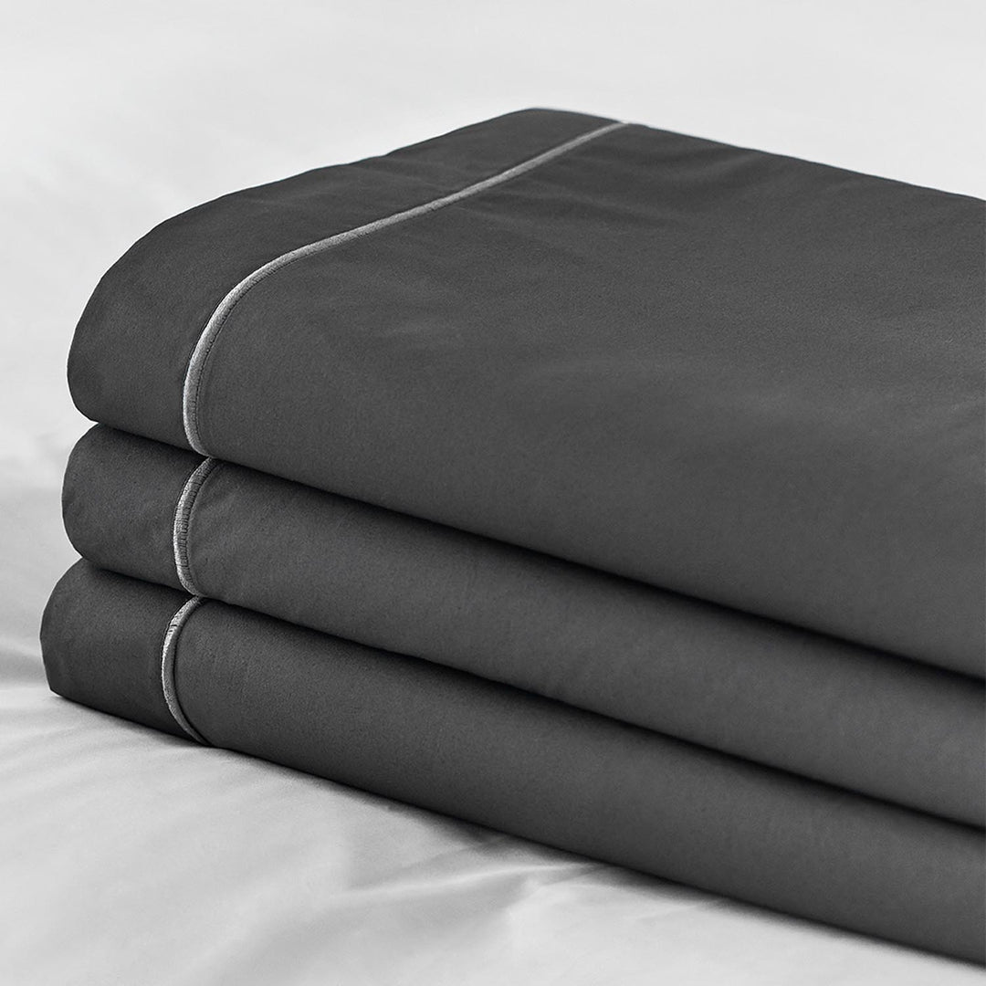 Stack of charcoal Egyptian cotton top sheets with light grey piping