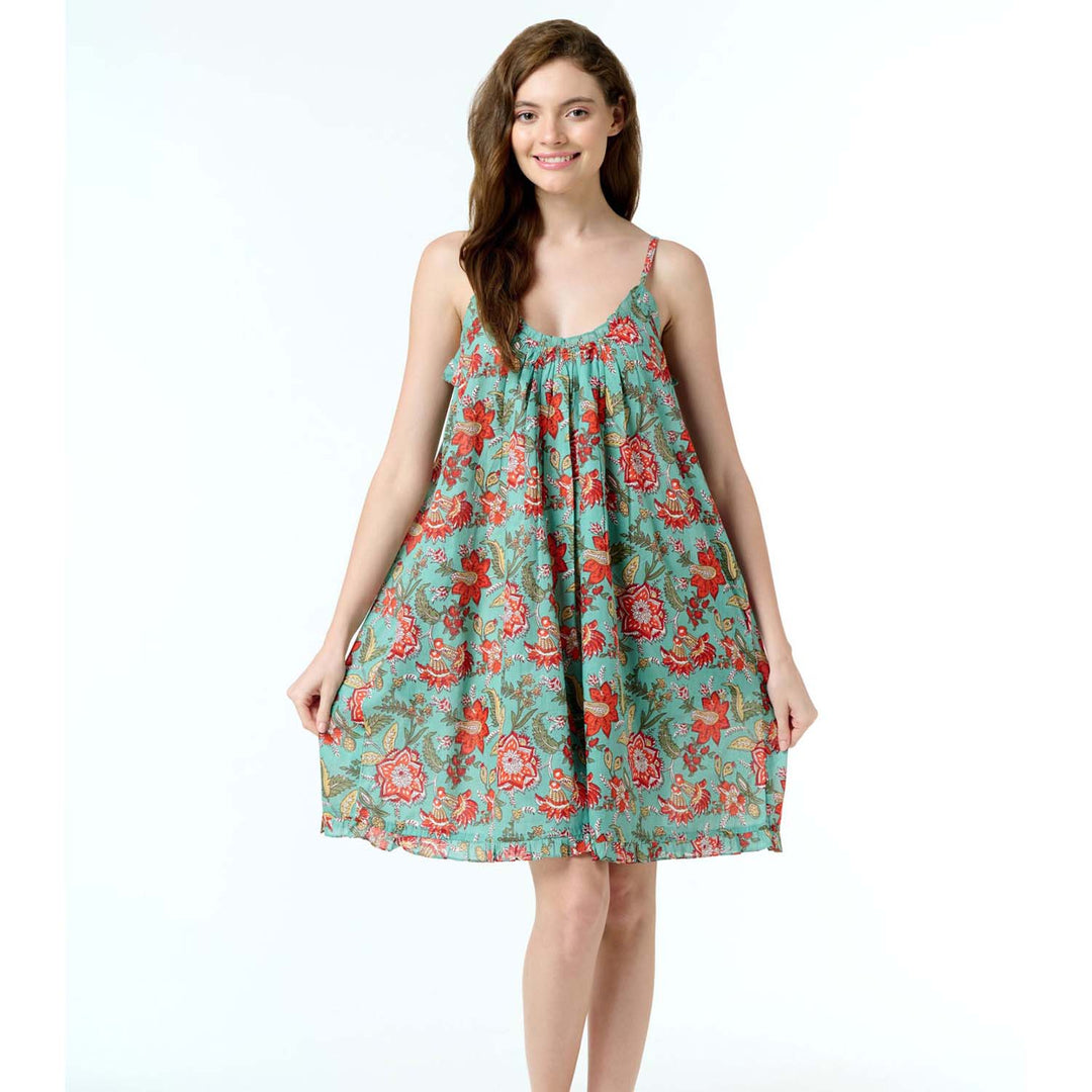 Woman wearing Belinda floral cotton nightie with pockets and frill trim, in teal and red print, standing against a white background