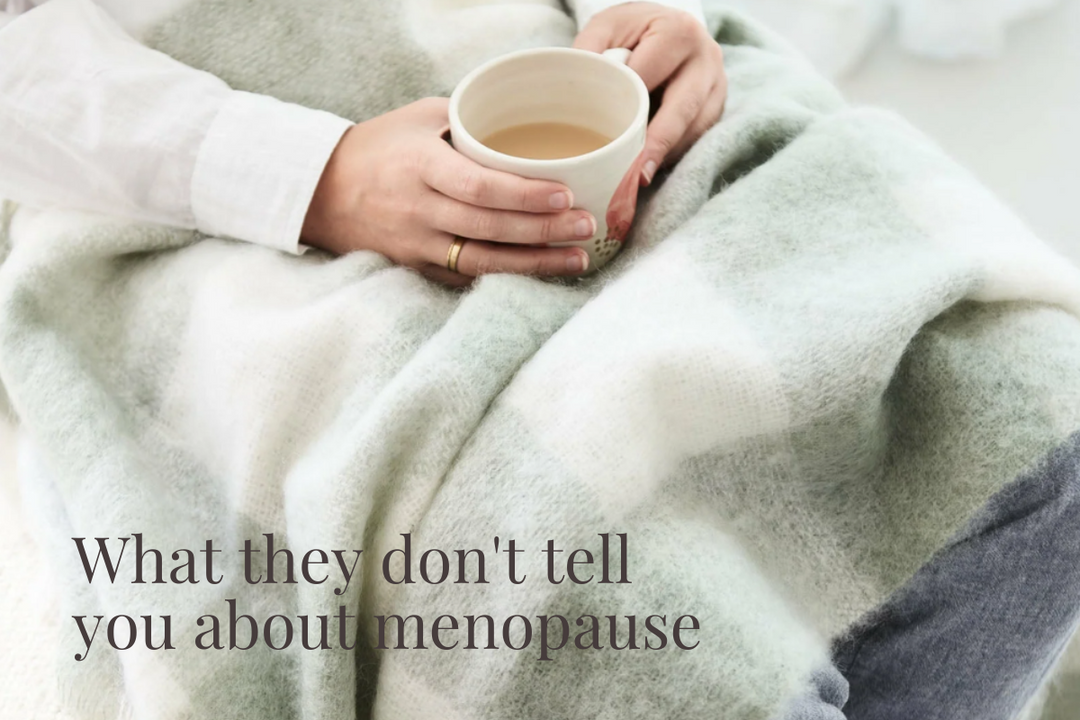 Woman holding tea wrapped in a soft wool blanket — menopause comfort and sleep support.
