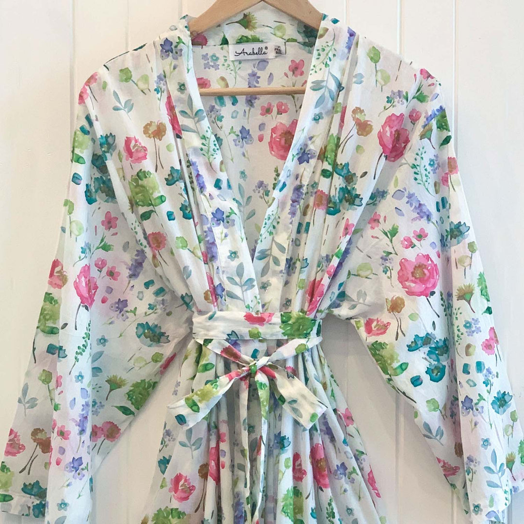 Alana floral cotton kimono tied at the waist and hanging on a wooden hanger against white timber wall