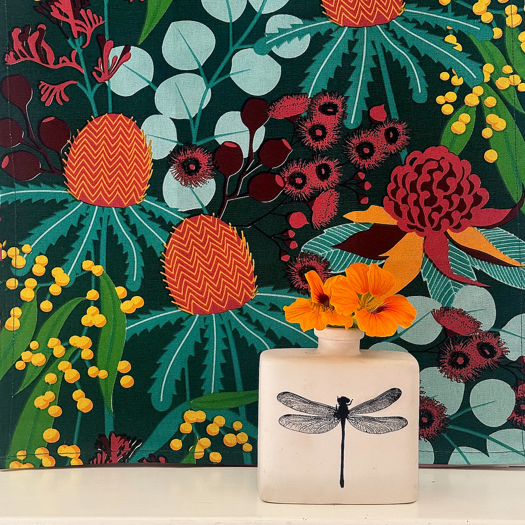 Decorative vase with a dragonfly design on a colorful floral background