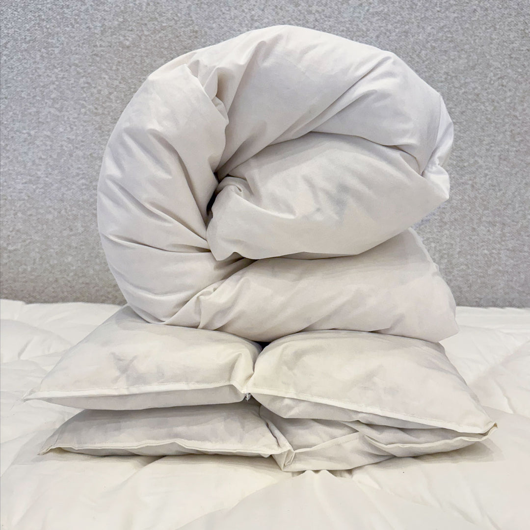 Stack of white pillows on a bed with a neutral background