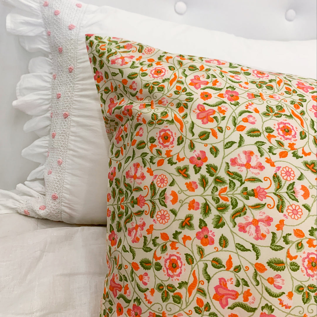 Floral patterned pillow on a white bed