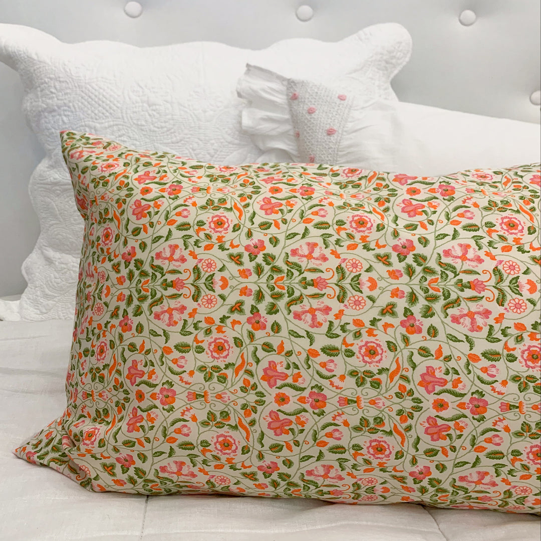 Floral patterned pillow on a bed with white pillows in the background