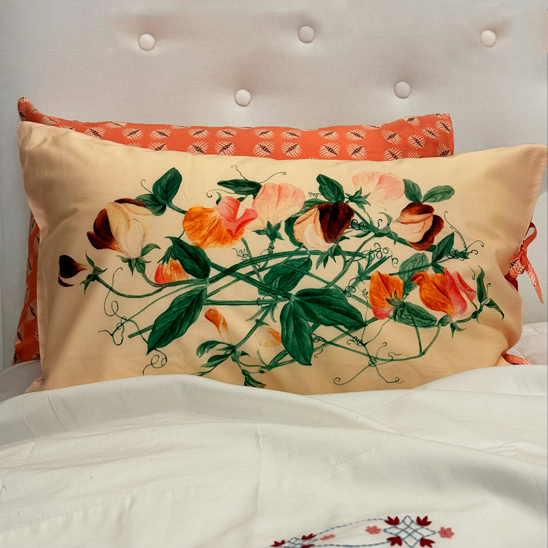 Decorative pillow with floral design on a bed with white bedding.