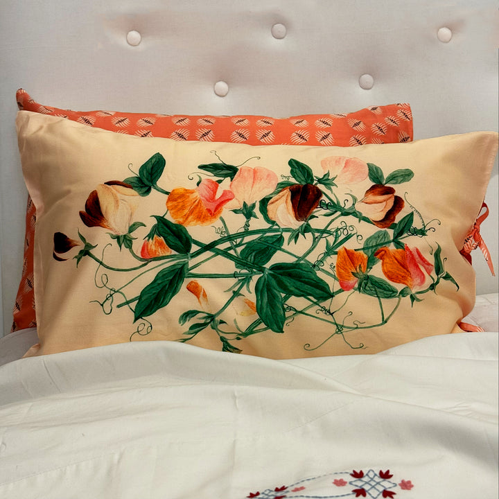 Decorative pillow with floral design on a bed with white bedding.