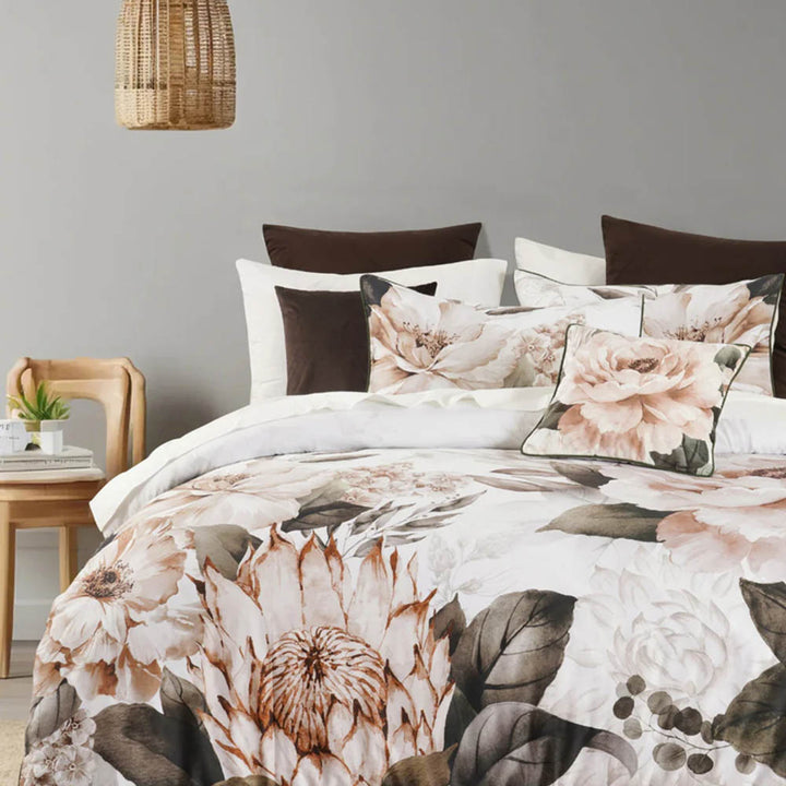 Floral bedding set on a bed with a gray wall and wooden chair in the background.