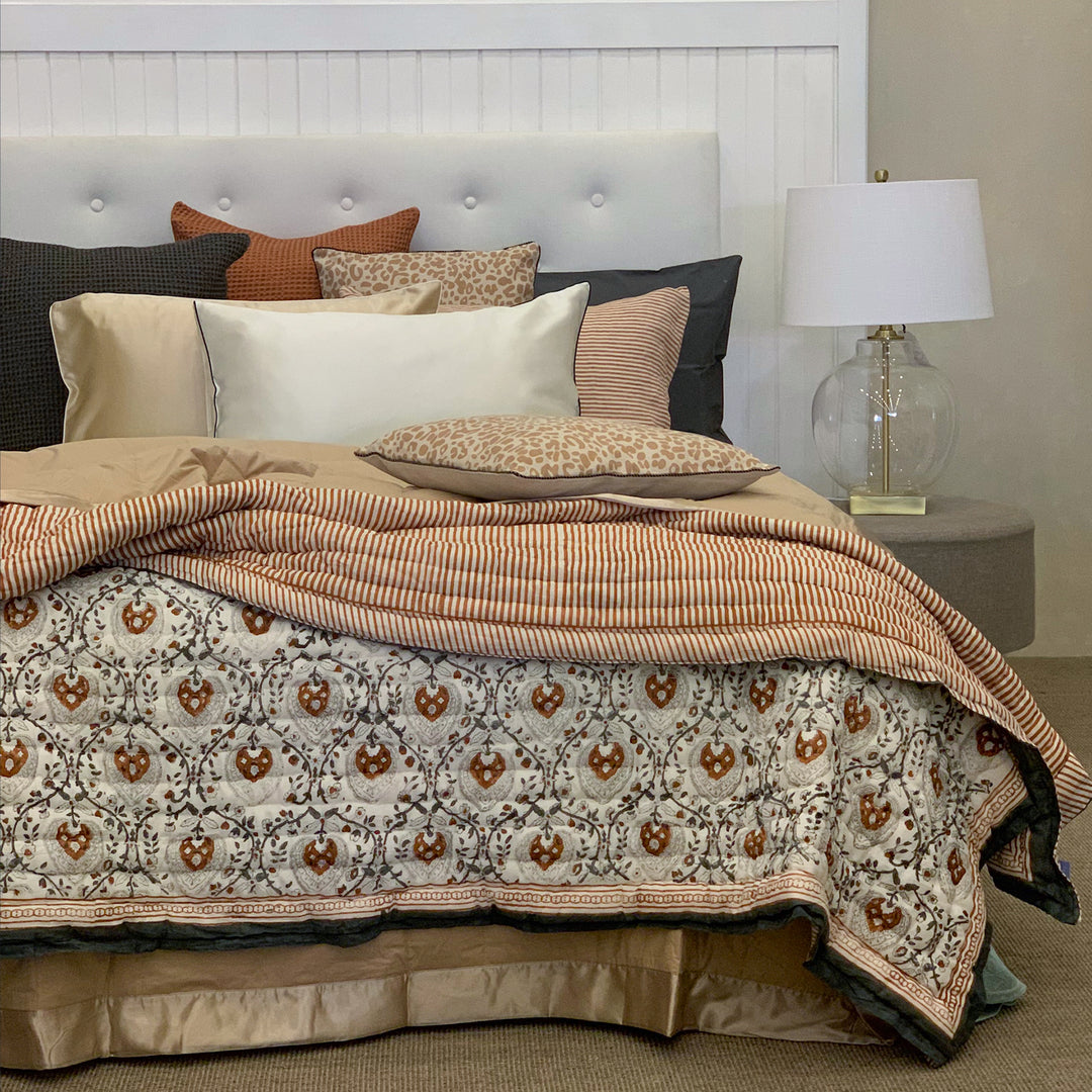 Bed with patterned comforter and pillows in a bedroom setting