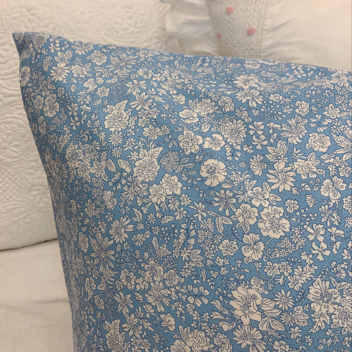 Floral-patterned blue pillow on a white background