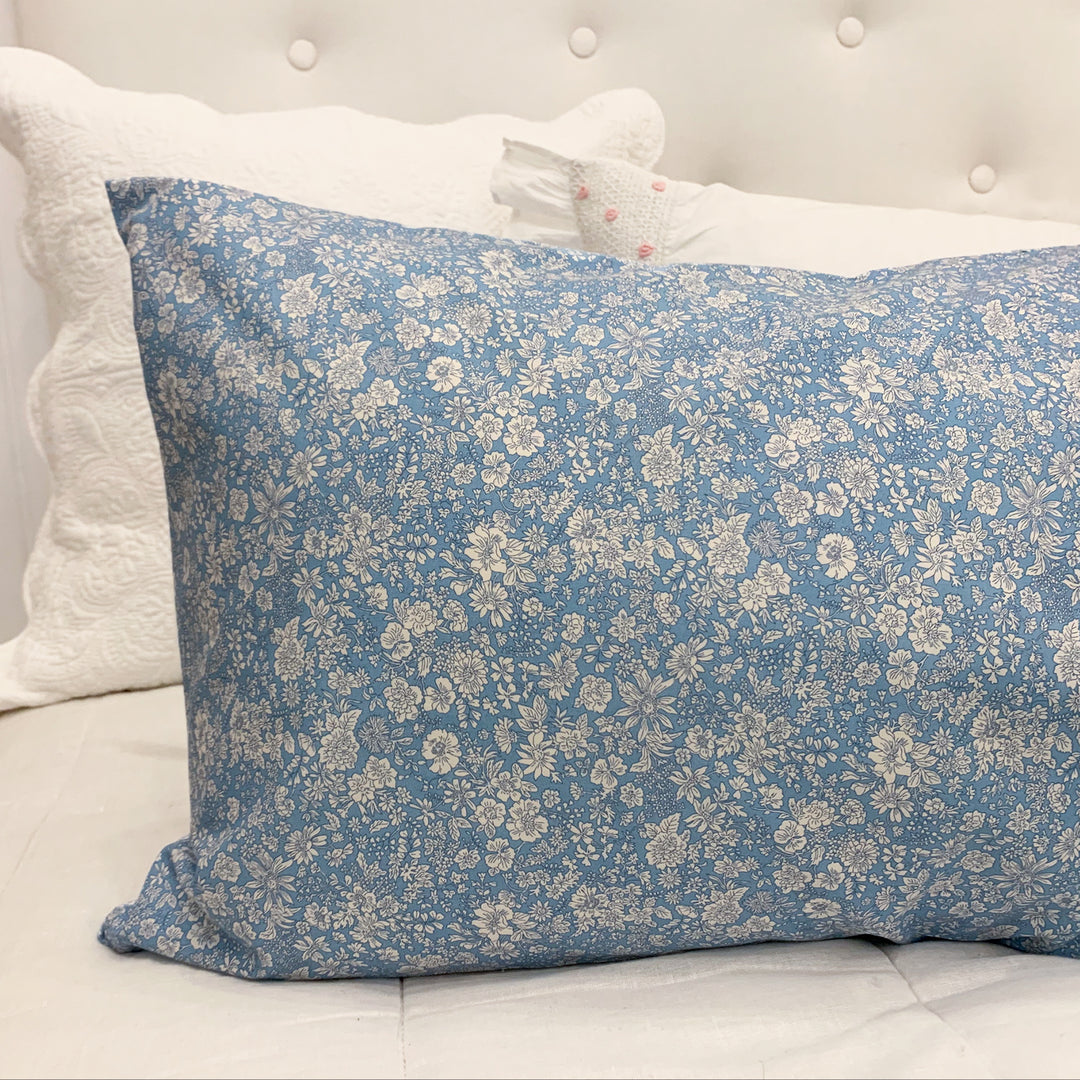 Blue floral pillow on a white bed