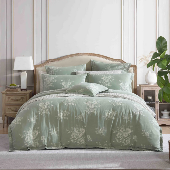 Elegant bedroom featuring sage green Maisey Moss quilt cover and layered cushions in a light, classic interior
