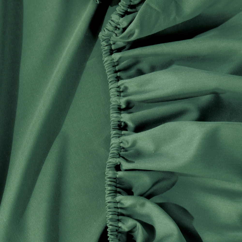 Close-up of elasticated edge on Bianca Forest Green fitted sheet, showcasing durable stitching and smooth cotton-bamboo fabric.