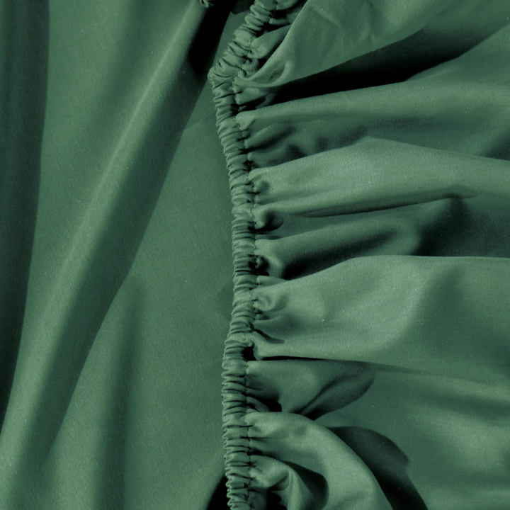 Close-up of elasticated edge on Bianca Forest Green fitted sheet, showcasing durable stitching and smooth cotton-bamboo fabric.