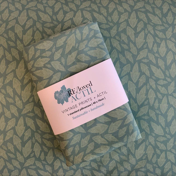 Flat lay of RE/Loved Actil Hollybush pillowcase in vintage green print, highlighting sustainable handmade packaging.