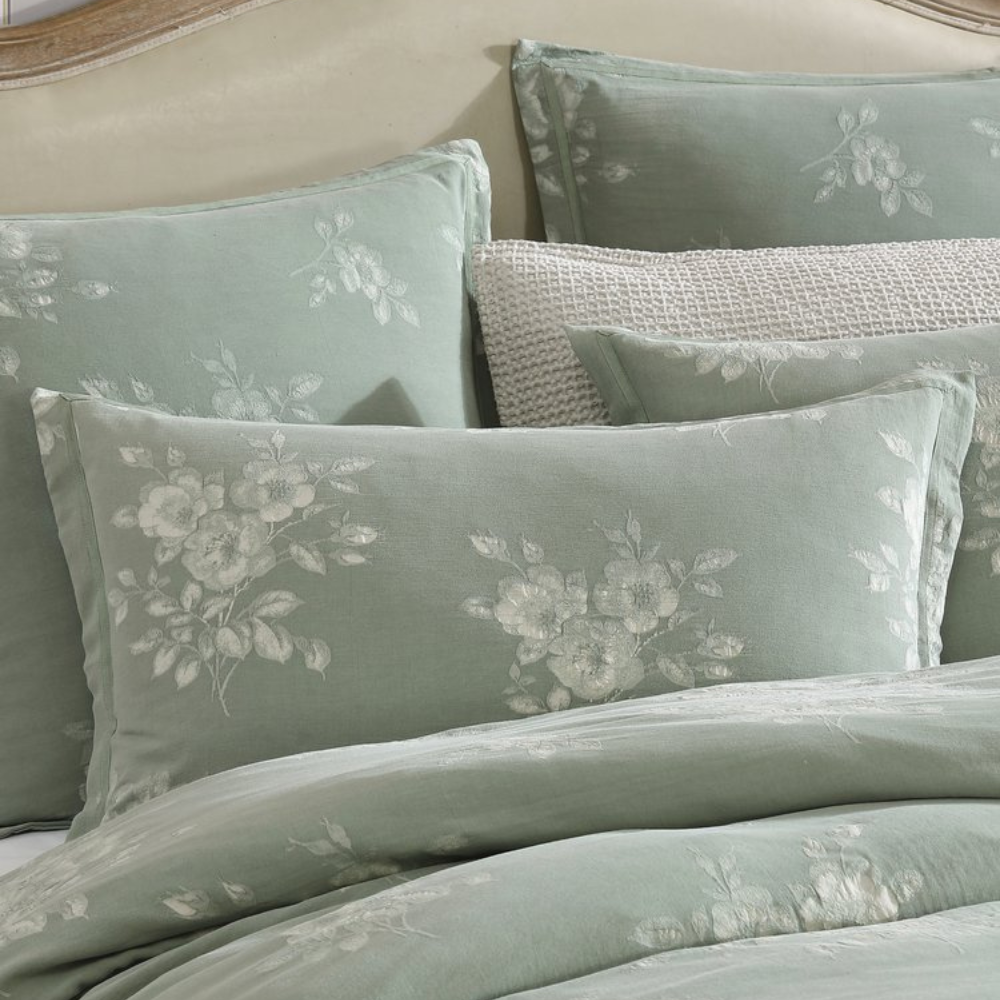 Floral patterned pillows and bedding set on a bed.