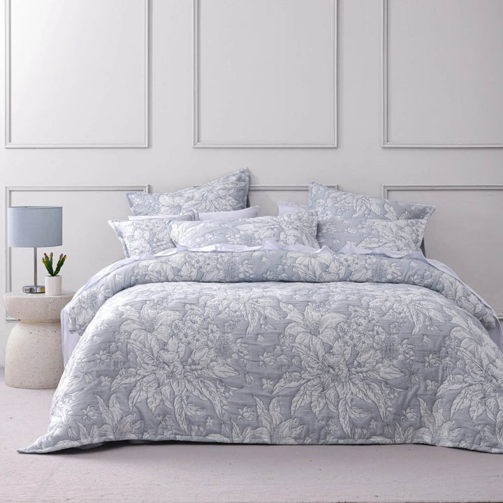 Floral patterned comforter set on a bed in a bedroom with a lamp and nightstand.