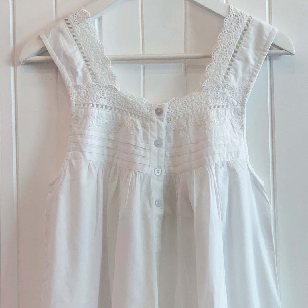 Classic white cotton nightdress with delicate lace trim and pintuck detail, displayed hanging in soft natural light.